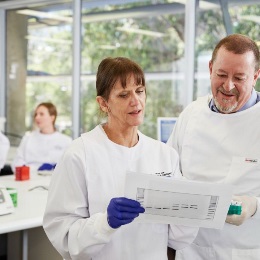 Two researchers wearing white lab coats analysing some results