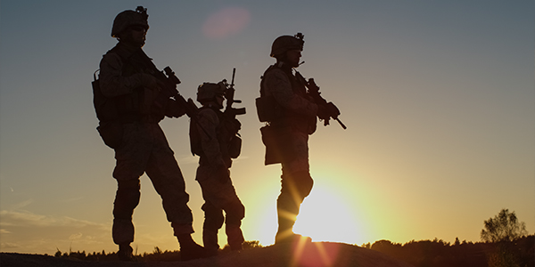 Military personnel in combat gear at sunset