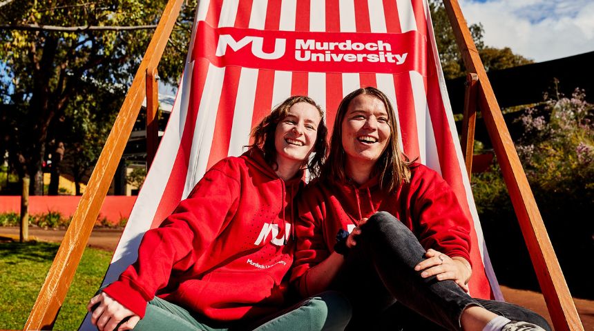 Two young, white females sitting on a giant deckchair