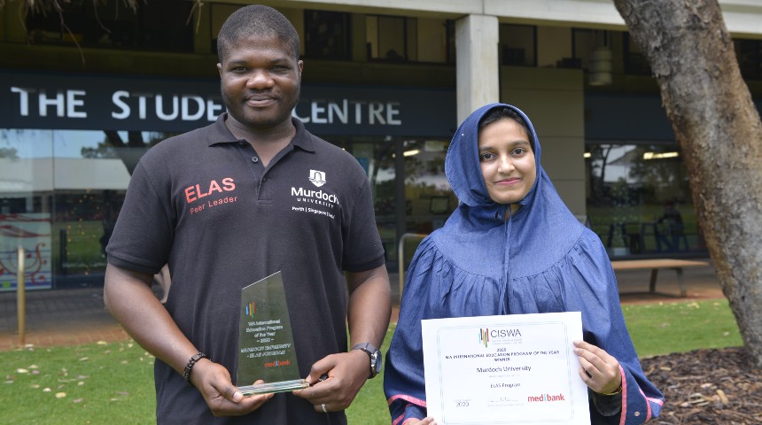 A man and woman holding certificates in front of the student centre