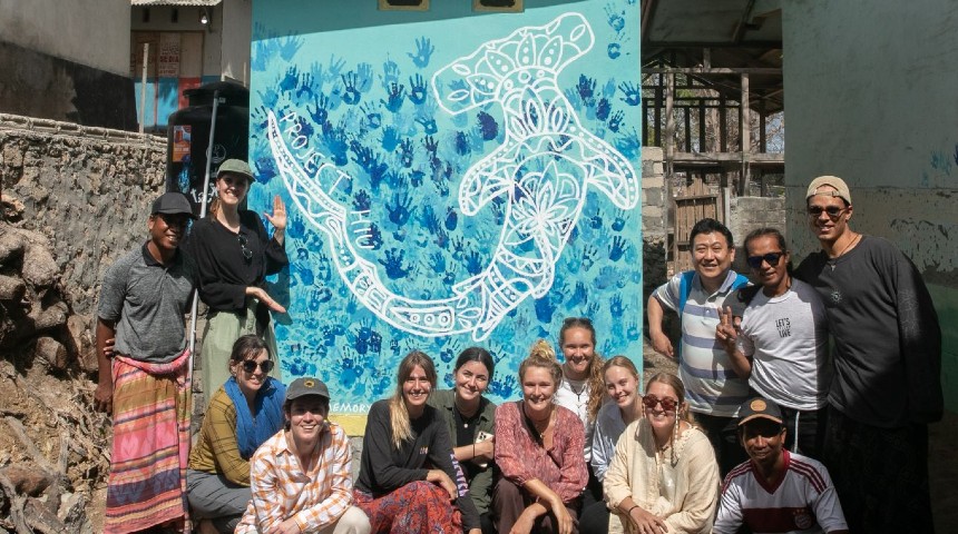 Murdoch students standing in front of hand painted shark mural in Indonesia.
