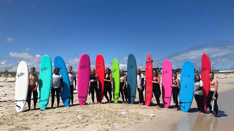 people standing on beach with surfboards