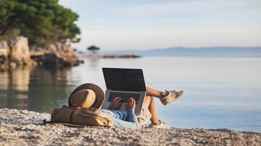 student with laptop by a lake
