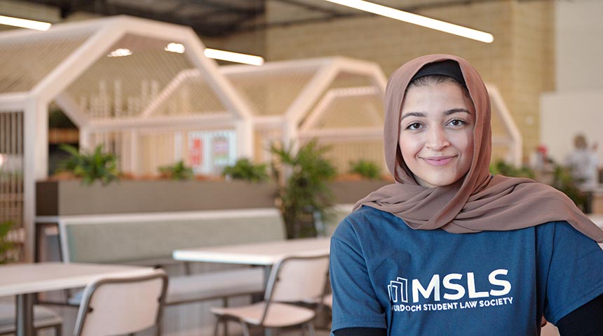 zahra smiling in blue murdoch student law society t shirt on the right side of the image