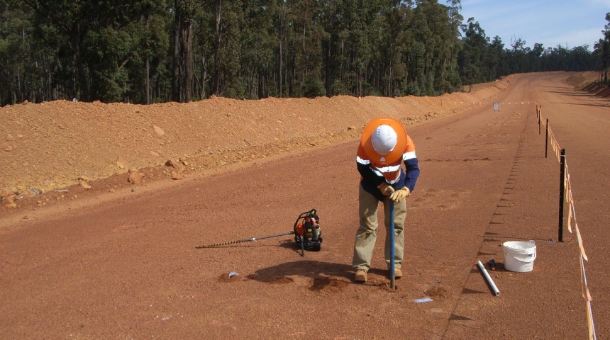 Researcher drills samples into a mining haul road