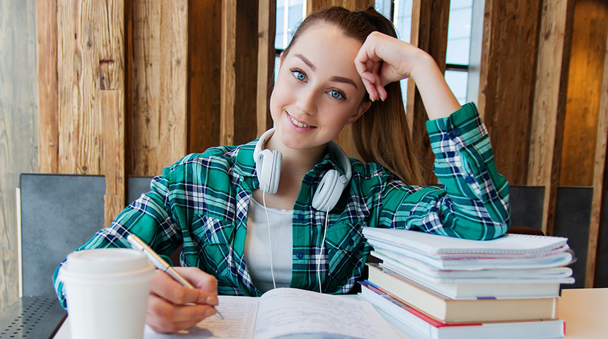 Young girl sitting at desk with notebook, books, and coffee