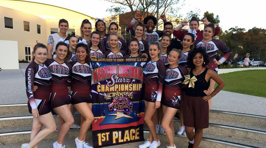 18 members of the Murdoch University Cheerleading Team in uniform, smiling and posing with a 1st place banner