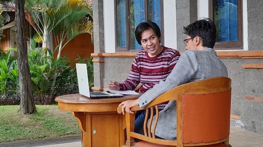 Student sits outside at a table with their laptop