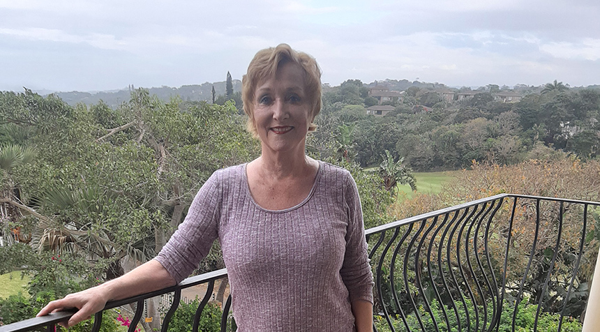 Cynthia stands on her balcony overlooking the South African jungle