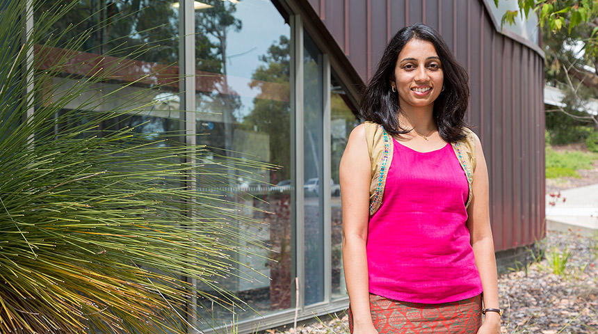 Student Deepa Machaiah posing and smiling outside building and grass tree at Murdoch