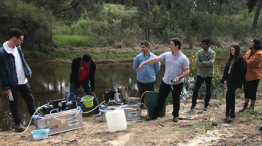 Students test a desalination machine on the banks of a river 