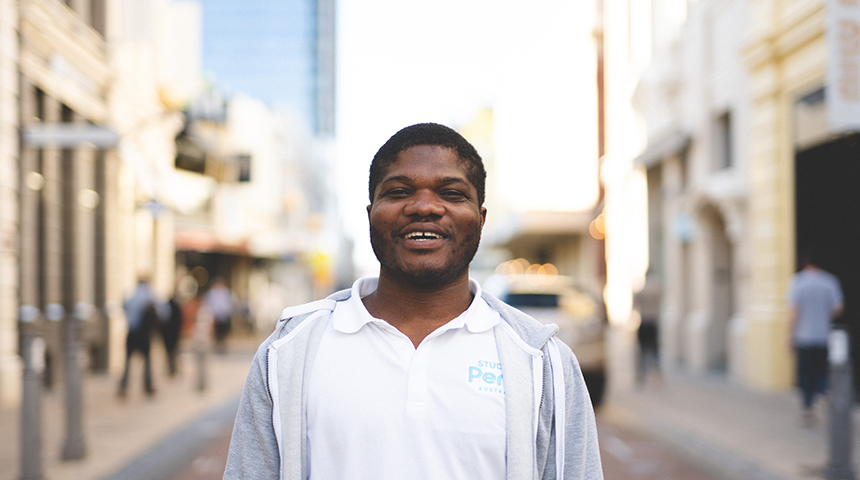 International student Emmanuel Dei standing and smiling on King Street, Perth