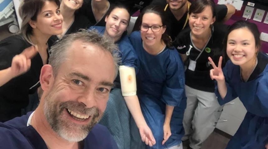 A group of Murdoch nursing students in scrubs smile to camera with their lecturer