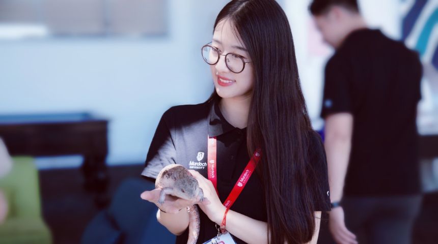 Murdoch student smiles while holding lizard