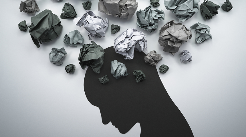 Silhouette of head looking down with scrunched up paper resembling thoughts