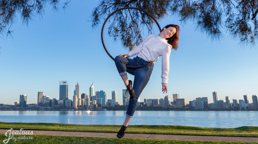 Dr Fleur van Rens balancing on a circus ring with the City of Perth in the background.