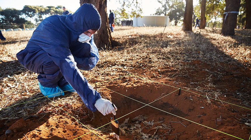 forensic student dusting evidence in sand