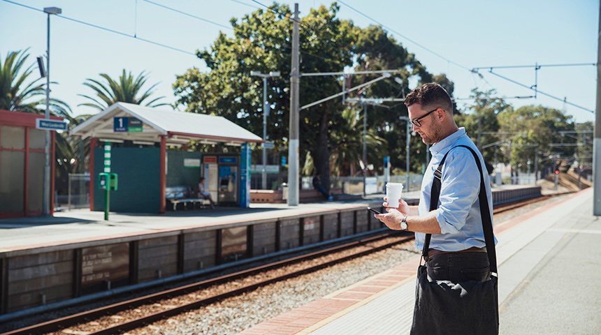 Man with a bag and coffee waiting at a Perth train station