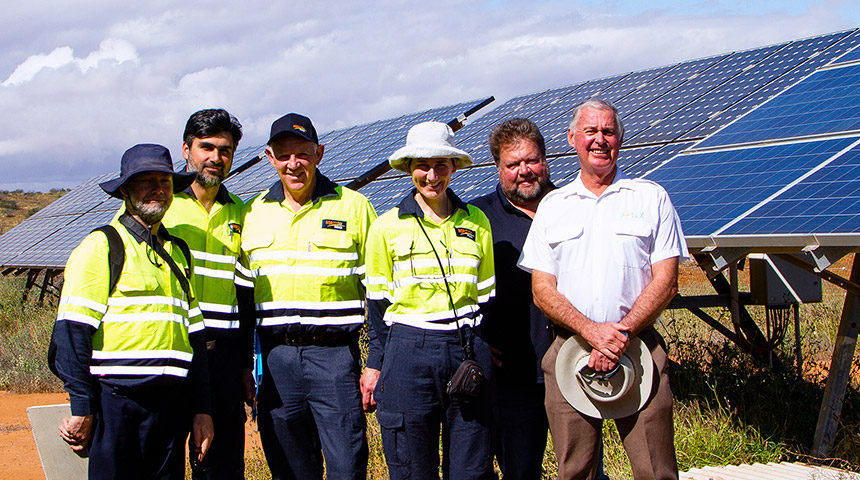 Group of people standing together with solar panels in the background
