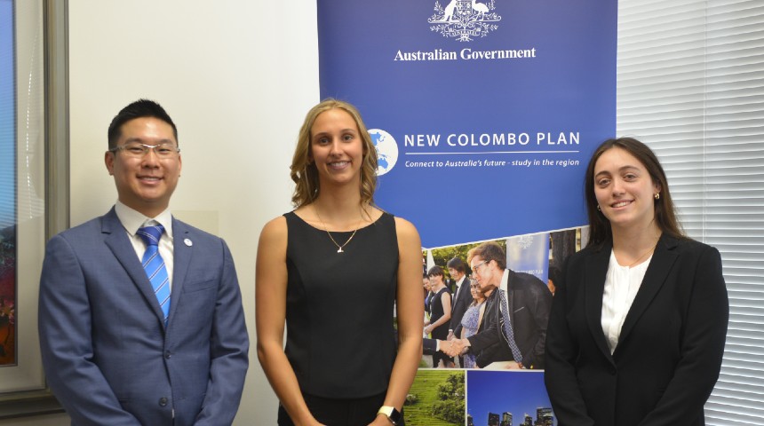 Three Murdoch students, recipients of the New Colombo Plan (NCP) Scholarship, stand in front of NCP banner 