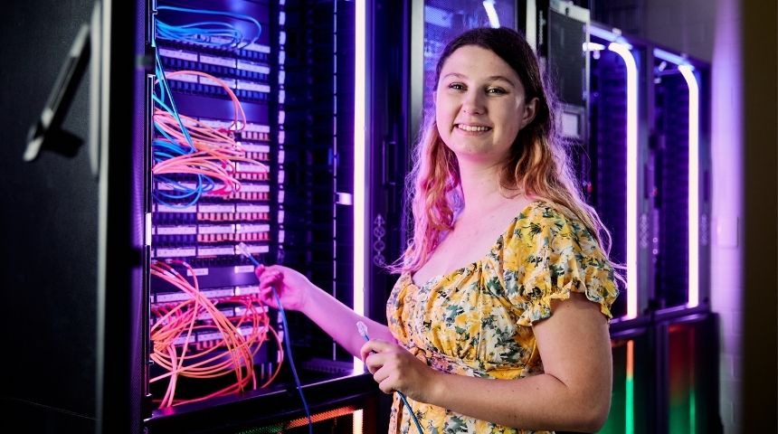 Student in information technology data centre smiles to camera