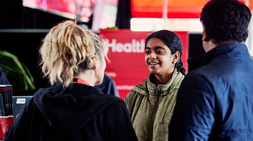Young woman chatting with female staff member at university open day