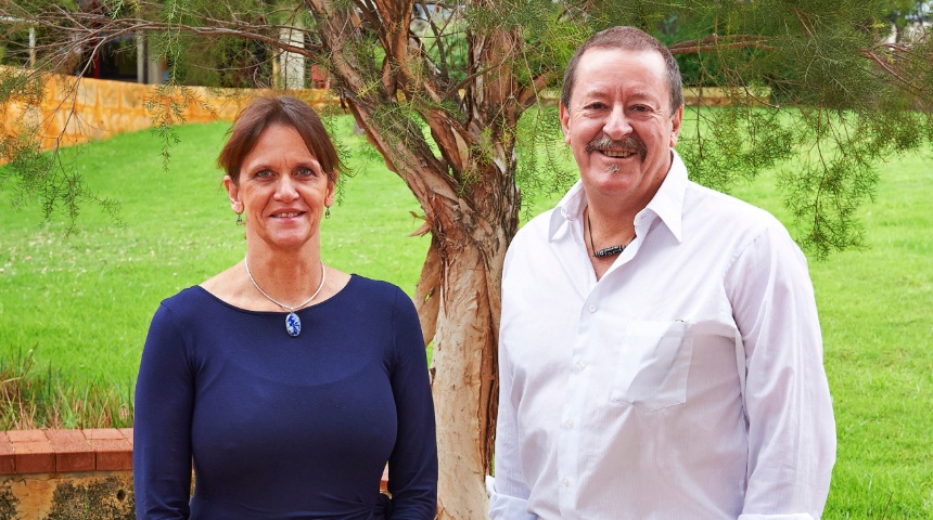 Professor Sue Fletcher and Professor Steve Wilton under a tree smiling at camera
