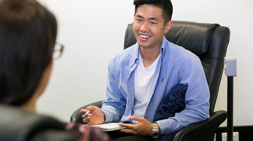Male student in a therapy session, smiling.