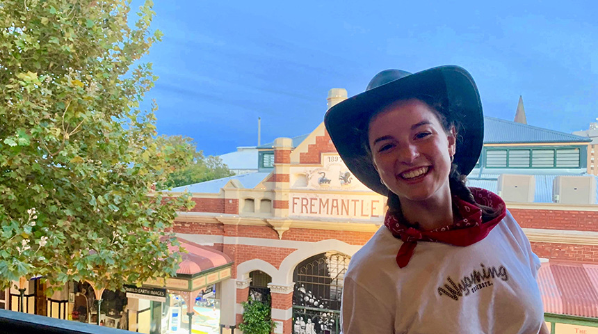 Young woman in cowboy hat and white t-shirt smiling and posing outside of Fremantle Markets