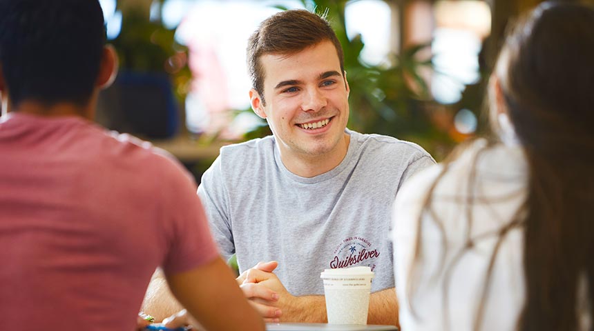 Murdoch student sitting with friends drinking coffee