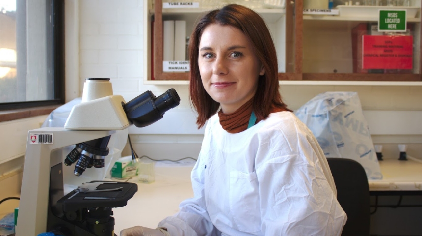Siobhon Egan sitting next to a microscope in the lab