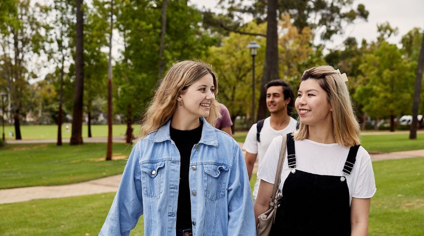 Two students walking on campus smiling at each other