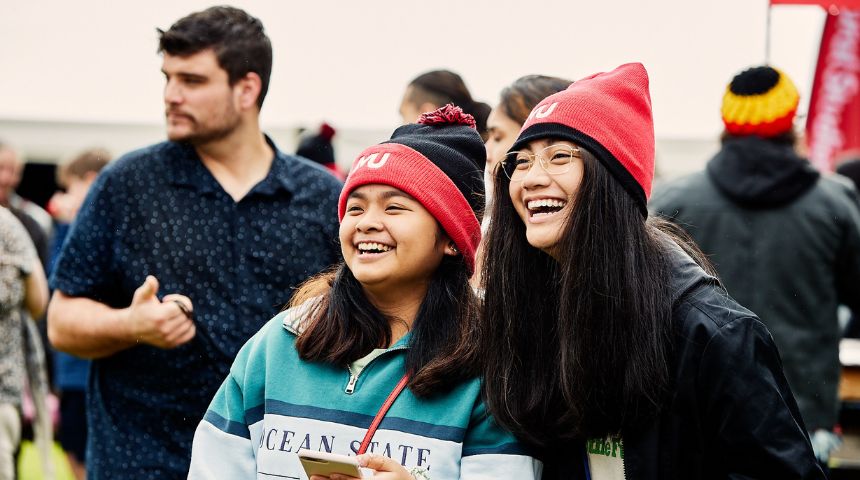 Two students wearing Murdoch Uni beanies smiling off camera