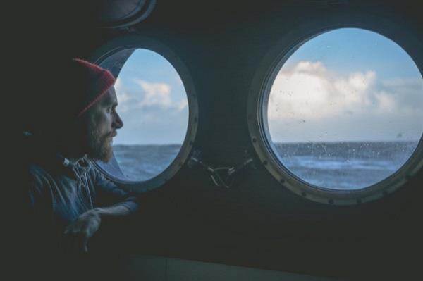 Man looking out window of ship