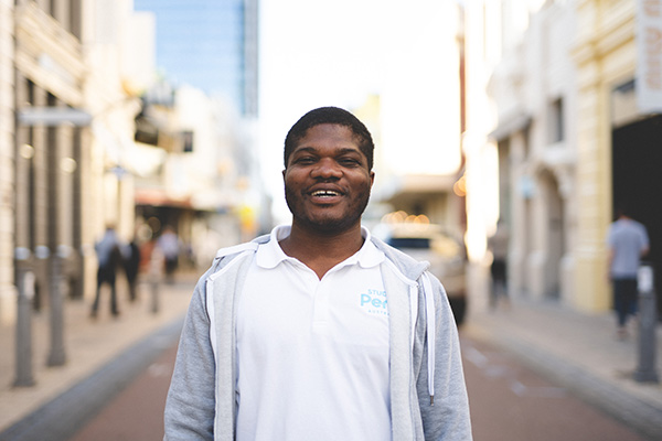 International student Emmanuel Dei standing and smiling on King Street, Perth