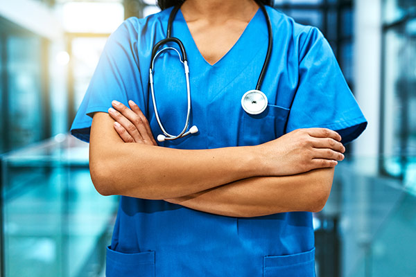 Nurse in blue uniform standing with arms crossed