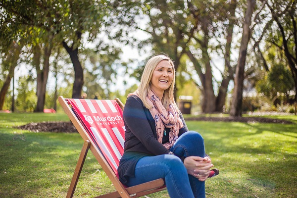 Joanne Padgett sits on a deckchair smiling on Murdoch University's bush court