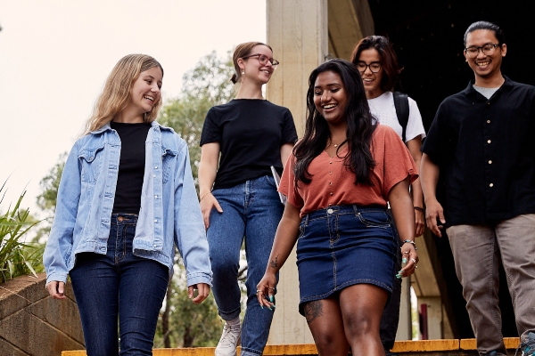 A group of students smiling and walking down some stairs.